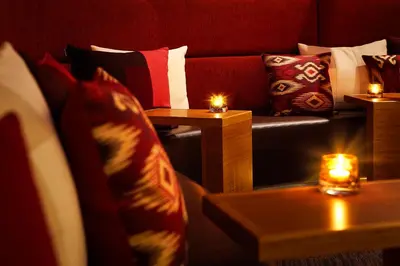 a living room with a red couch with candles on tables at Hyatt Place Amsterdam Airport in Hoofddorp