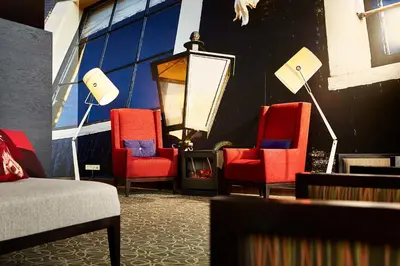 a living room with red chairs and a lamp at Hyatt Place Amsterdam Airport in Hoofddorp