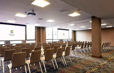 an empty room with chairs and a projection screen at Hyatt Place Amsterdam Airport in Hoofddorp
