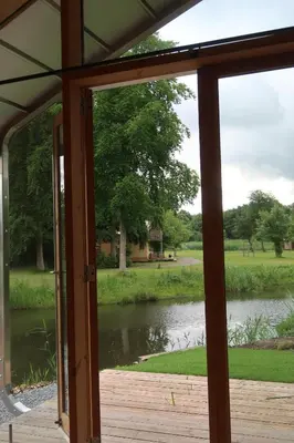 a view of a lake from a screened in porch at De Parel - Mystical spaces to discover! in Zeewolde