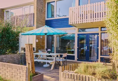 a table with an umbrella in front of a building at Seapaerdje in Bergen aan Zee