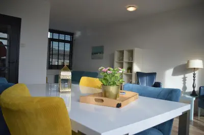 a dining room with a table with a vase of flowers on it at Seapaerdje in Bergen aan Zee