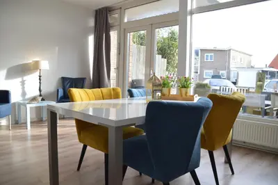 a dining room with a table and yellow chairs at Seapaerdje in Bergen aan Zee