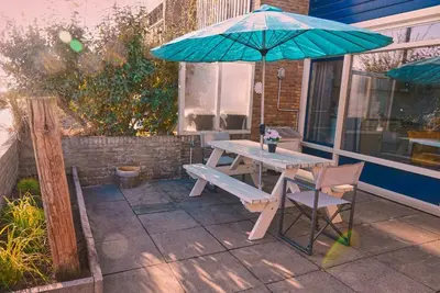a picnic table and a blue umbrella on a patio at Seapaerdje in Bergen aan Zee