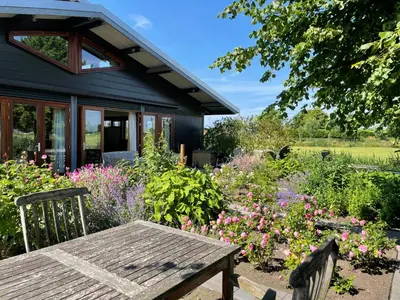 a wooden table in a garden with flowers at Hestar Husid, het luxe paardenhuis in Weesp
