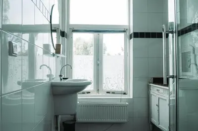 a white bathroom with a sink and a window at Bed and Breakfast du Parc in Zaandam