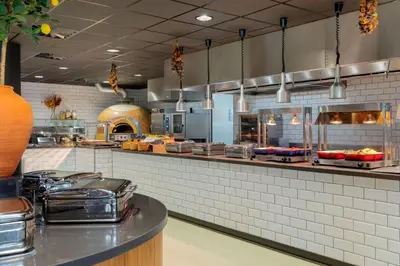 a large kitchen with a counter in a restaurant at Corendon Amsterdam Schiphol Airport, a Tribute Portfolio Hotel in Badhoevedorp