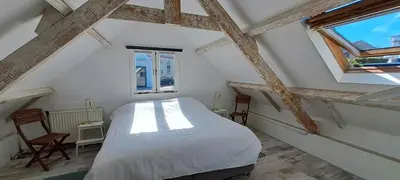 a bedroom with a white bed and two windows at zilvermeeuw in Bergen aan Zee