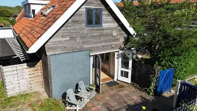 a small house with a door and two chairs at zilvermeeuw in Bergen aan Zee
