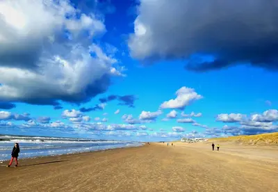 a beach with people walking on the sand at zilvermeeuw in Bergen aan Zee