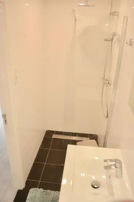 a white bathroom with a shower and a sink at De Wulk 26 in Zandvoort