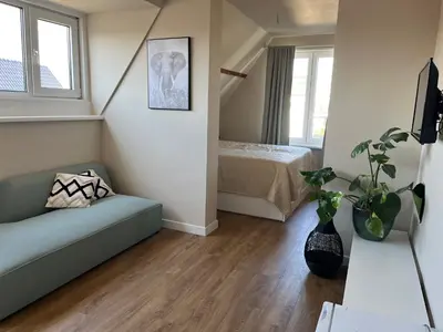 a living room with a couch and a bed at Weltevreden in Noordwijk