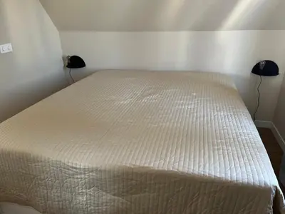 a white bed in a room with two lamps at Weltevreden in Noordwijk