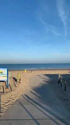 a sandy beach with a sign and the ocean at Weltevreden in Noordwijk