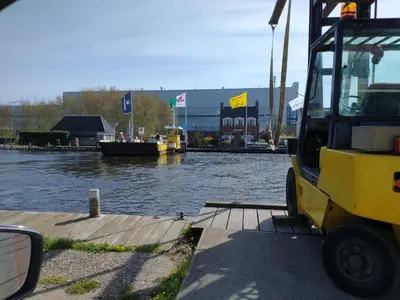 a yellow truck parked next to a body of water at B&Bslapenopeeneiland in Kaag