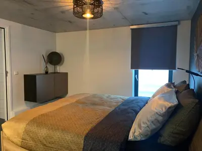 a bedroom with a bed and a lamp and a window at Strand en meer in Katwijk aan Zee