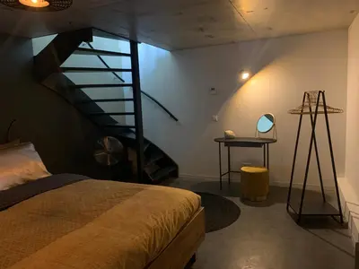 a room with a bed and a spiral staircase at Strand en meer in Katwijk aan Zee