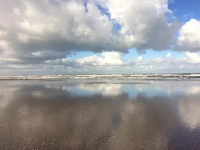 a view of a beach with a cloudy sky and water at Strand en meer in Katwijk aan Zee