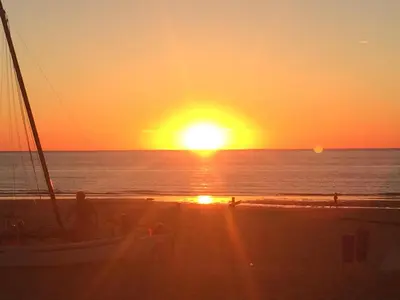 a sunset on the beach with a boat on the beach at Strand en meer in Katwijk aan Zee