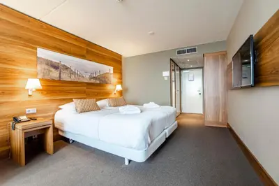 a hotel room with a bed and a television at Suite with stunning sea view in Zandvoort