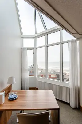 a dining room with a table and a large window at Suite with stunning sea view in Zandvoort
