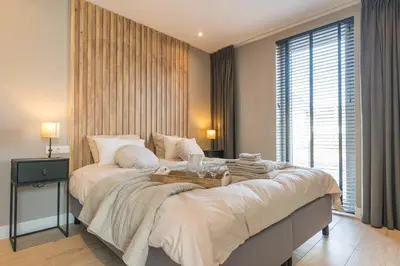 a large bed in a room with a large window at Luxe appartement dichtbij strand en zee, in het hart van de bollenstreek in Noordwijkerhout