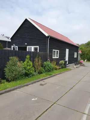 a black house with a red roof on a street at Tjotter in Amsterdam