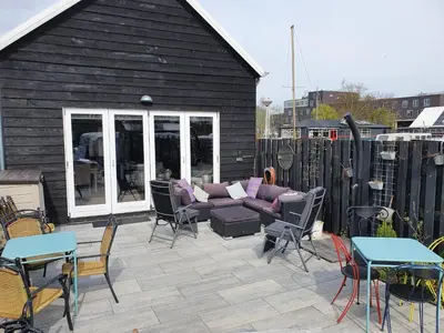 a patio with a couch and chairs and tables at Tjotter in Amsterdam