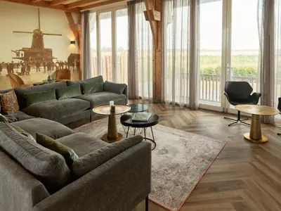 a living room with a couch and tables and windows at Dutchen Erfgoedpark De Hoop Vakantiewoningen in Uitgeest
