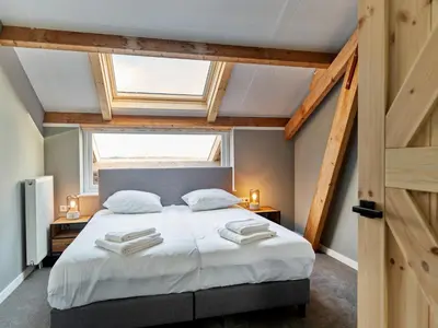 a bedroom with a large bed and a window at Dutchen Erfgoedpark De Hoop Vakantiewoningen in Uitgeest