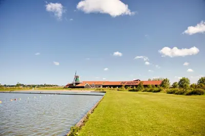 a pond with ducks in front of a building at Dutchen Erfgoedpark De Hoop Vakantiewoningen in Uitgeest