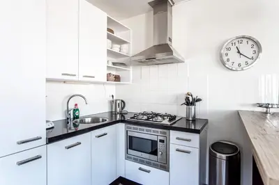 a kitchen with white cabinets and a clock on the wall at Kaag Resort in Warmond