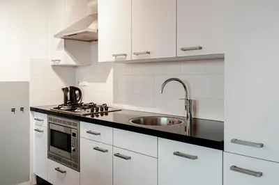 a kitchen with white cabinets and a sink at Kaag Resort in Warmond