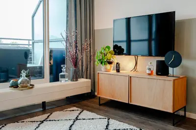 a living room with a large flat screen tv on a cabinet at Kaag Resort in Warmond