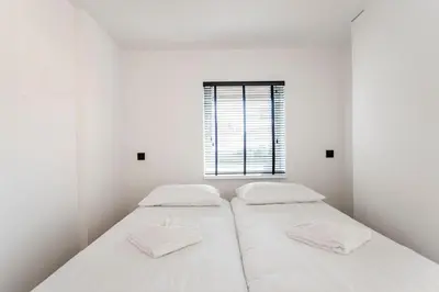 two beds in a white room with a window at Studio Thor, With free parking in Zandvoort
