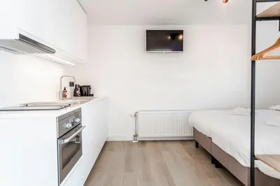 a small bedroom with a bed and a kitchen at Studio Thor, With free parking in Zandvoort