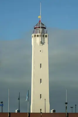 a white lighthouse with a flag on top of it at De Kroft Beach Residences Noordwijk aan Zee in Noordwijk