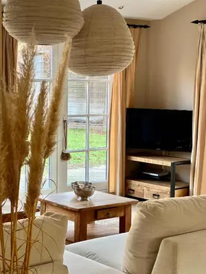 a living room with a couch and a large window at De Kroft Beach Residences Noordwijk aan Zee in Noordwijk