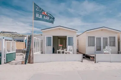 a beach house on the sand with a flag at Rijk aan Zee Ecolodges in Wijk aan Zee