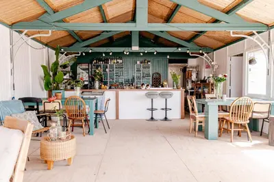 a patio with tables and chairs and a bar at Rijk aan Zee Ecolodges in Wijk aan Zee