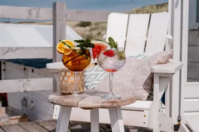 two glasses of fruit on a table on a chair at Rijk aan Zee Ecolodges in Wijk aan Zee