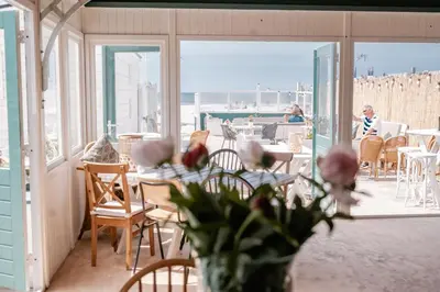 a room with tables and chairs and a balcony with people at Rijk aan Zee Ecolodges in Wijk aan Zee