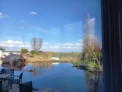 a window view of a river with a boat in it at Pura Vida del Rio in Oud-Ade