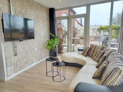 a living room with a couch and a tv at Pura Vida del Rio in Oud-Ade