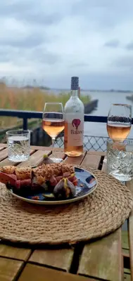 a table with a plate of food and two glasses of wine at Plassenzicht Logies & Sloepverhuur in Loosdrecht