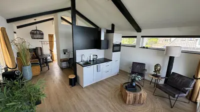 a living room with a kitchen and a living room with a table at Plassenzicht Logies & Sloepverhuur in Loosdrecht