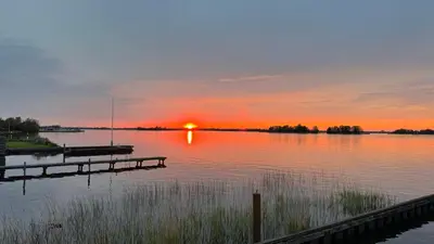 a sunset over a lake with a dock at Plassenzicht Logies & Sloepverhuur in Loosdrecht