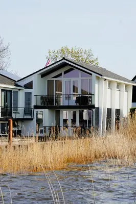a house on the banks of a body of water at Plassenzicht Logies & Sloepverhuur in Loosdrecht