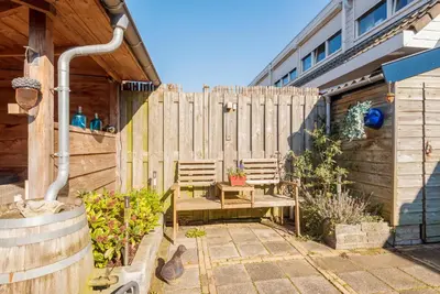 a patio with two benches in front of a fence at De Zonnestraal in Bergen