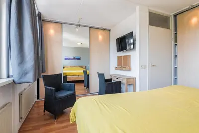 a bedroom with a bed and two chairs and a table at De Zonnestraal in Bergen